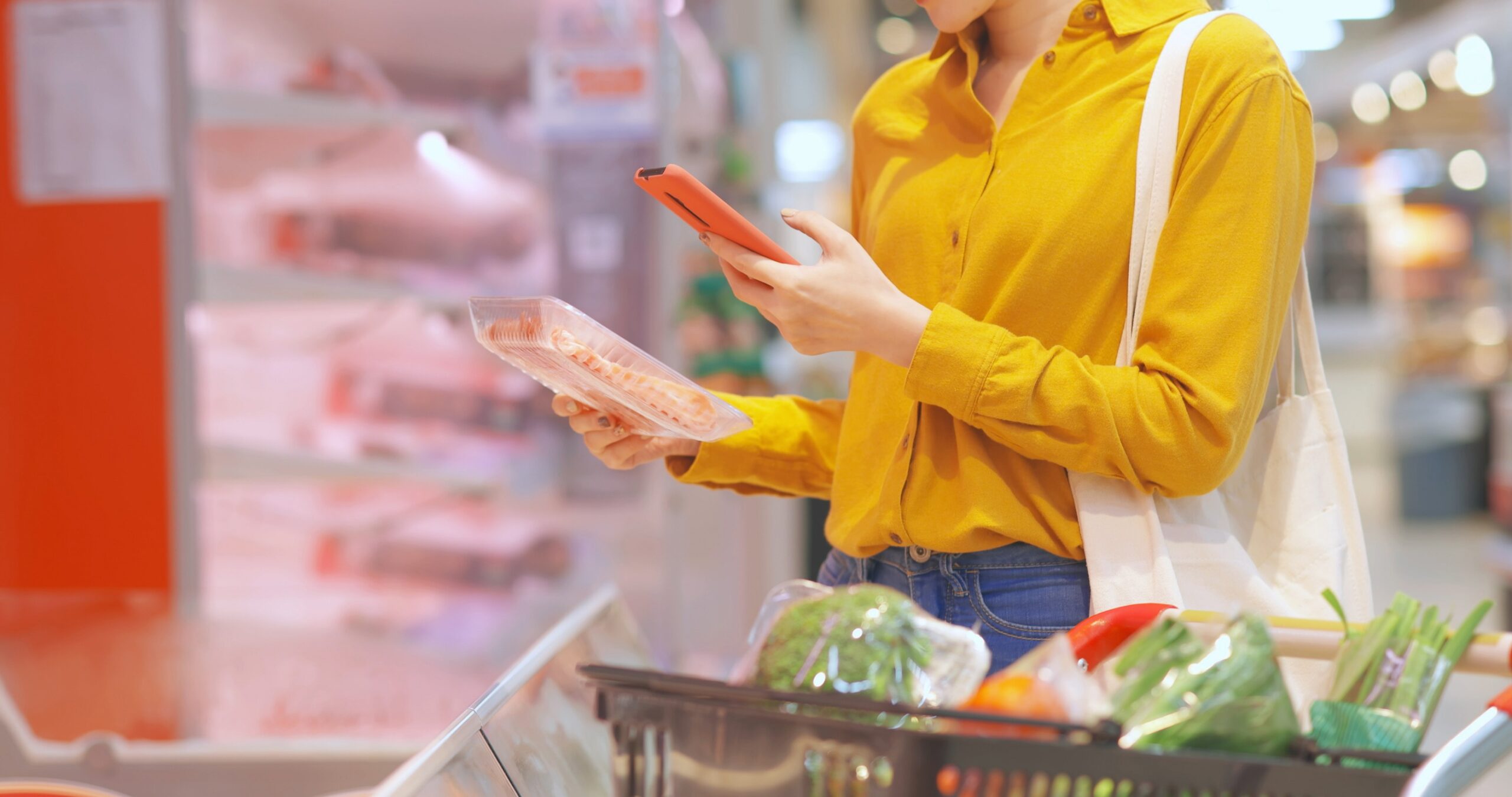 close up of asian young businesswoman is shopping for meat and scanning barcode with smart phone at supermarket